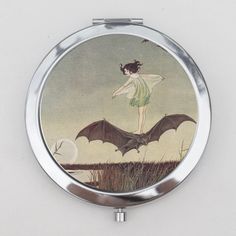 a compact mirror with a painting of a woman flying a bat