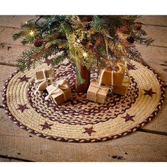 a christmas tree with presents under it sitting on a round rug next to a small pine tree