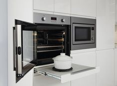 an open microwave oven sitting on top of a counter in a kitchen with white cabinets