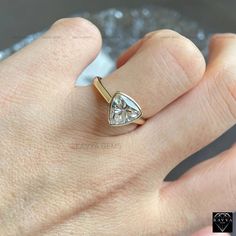 a person's hand with a gold and white diamond ring on top of it