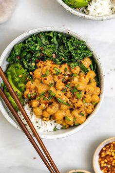 a bowl filled with rice, meat and vegetables next to chopsticks on the side