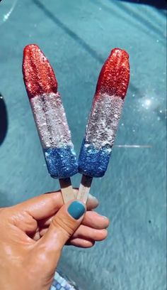 someone is holding two popsicles with red, white and blue toppings on them