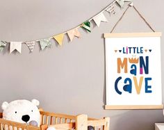 a teddy bear sitting in a crib next to a sign that says little man cave