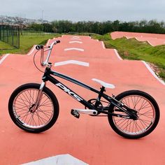 a black and white bike parked on top of a pink skateboard park slope area