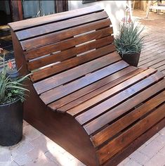 a wooden bench sitting on top of a brick floor next to potted planters