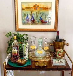 a table topped with bottles and glasses on top of a wooden table next to a painting