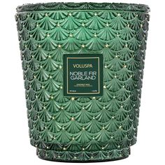 a candle that is green and has gold trimmings on the top of it