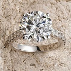 a diamond ring sitting on top of a stone wall next to a white sand background