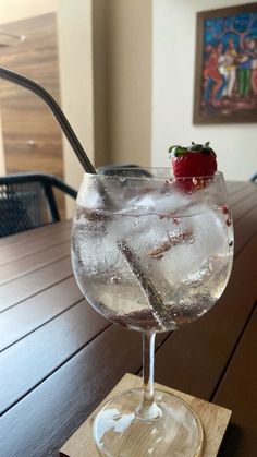 a glass filled with ice and strawberries on top of a wooden table