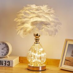 a lamp that is on top of a table next to some pictures and a clock