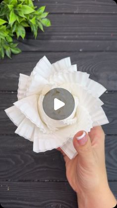 a person is holding a paper flower with a video playing button on the center piece