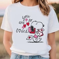 a woman wearing a t - shirt that says you are so loved with a snoopy holding