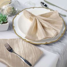 a table setting with napkins, silverware and succulents