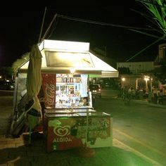 a food cart sitting on the side of a road at night