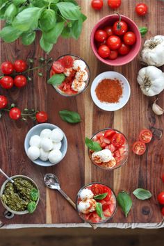 tomatoes, basil, mozzarella and other ingredients on a cutting board with spoons