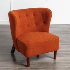 an orange chair sitting on top of a hard wood floor next to a white wall