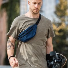 a man carrying a skateboard while wearing a fanny bag