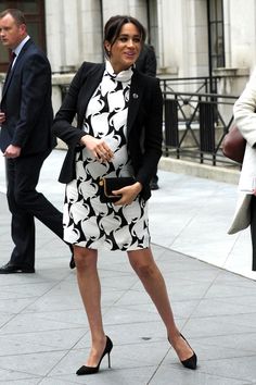 the pregnant woman is walking down the street in her black and white dress with heels