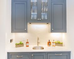 a kitchen with gray cabinets and white counter tops