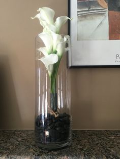 there is a vase with some flowers in it on the counter next to a picture