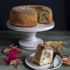 a bundt cake on a plate with a slice taken out of it and autumn leaves