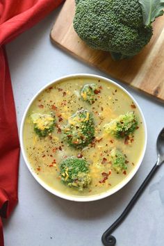 a bowl of broccoli and cheese soup on a cutting board