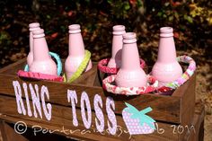 four pink soda bottles in a wooden crate with the word ring toss on it's side