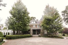 a large house with lots of trees and bushes around it's front entrance area