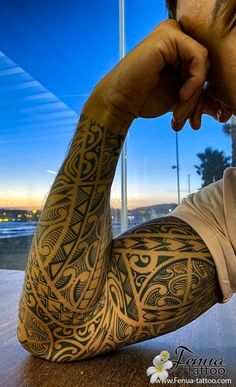 a man sitting at a table with his arm covered in tattoos