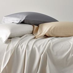 a bed with white sheets and pillows on top of it