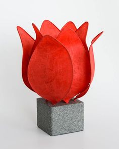 a red sculpture sitting on top of a cement block