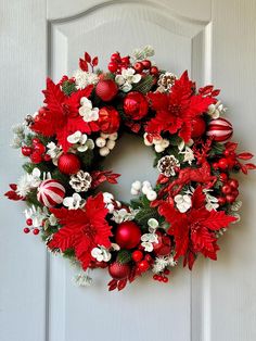 a red and white christmas wreath hanging on the front door with ornaments around it's edges