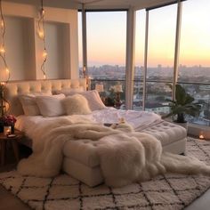 a large bed sitting in the middle of a bedroom next to a window with lights on it