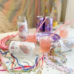 several bottles and glasses on a table with beaded necklaces, beads, and other confetti