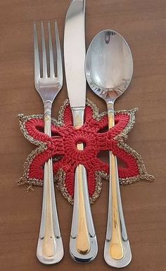 four forks, two spoons and one knife are on a table with a red doily