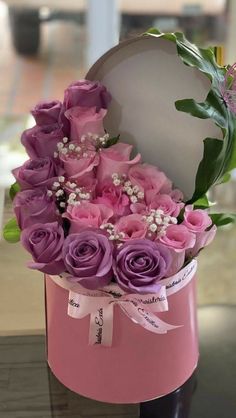 a pink hat box with purple roses and baby's breath