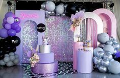 a purple and silver birthday party with balloons on the wall, cake table and decorations