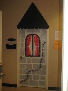 a door decorated to look like a house with a window and red curtains on it