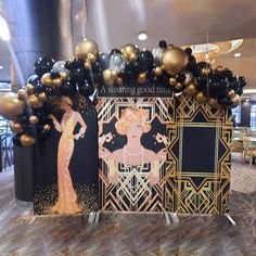 a black and gold themed table with balloons in the shape of art deco women on it