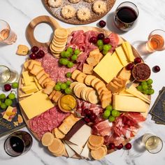 an assortment of cheeses, meats and crackers arranged on a platter