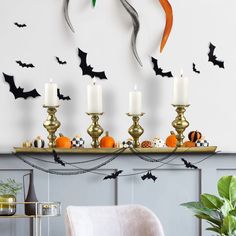 a mantle with candles and bats on it in front of a wall decorated with halloween decorations