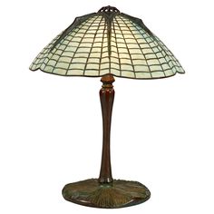 a lamp that is sitting on top of a wooden stand with a glass shade over it