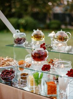 an assortment of teas and nuts on display in a glass case with lights at the top