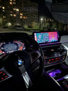 the interior of a bmw car at night with its dashboard and infotain illuminated by colorful lights