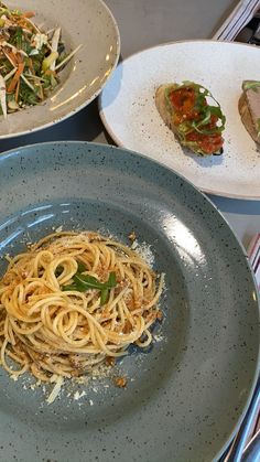 three plates of food on a table with silverware and utensils in the background