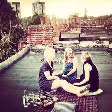 three women sitting on the roof talking to each other