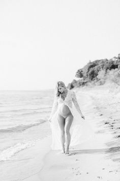 a woman in a wedding dress walking on the beach