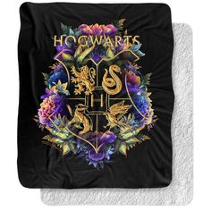 the hogwarts crest is surrounded by flowers and leaves on a black flee blanket