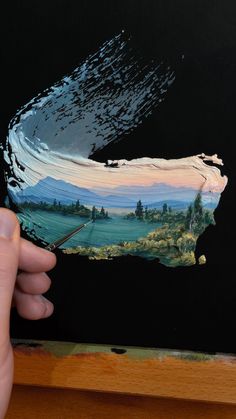 a person holding up a piece of art that has been painted with acrylic paint