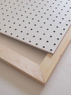 a piece of wood with holes in it on top of a white surface, next to a wooden frame